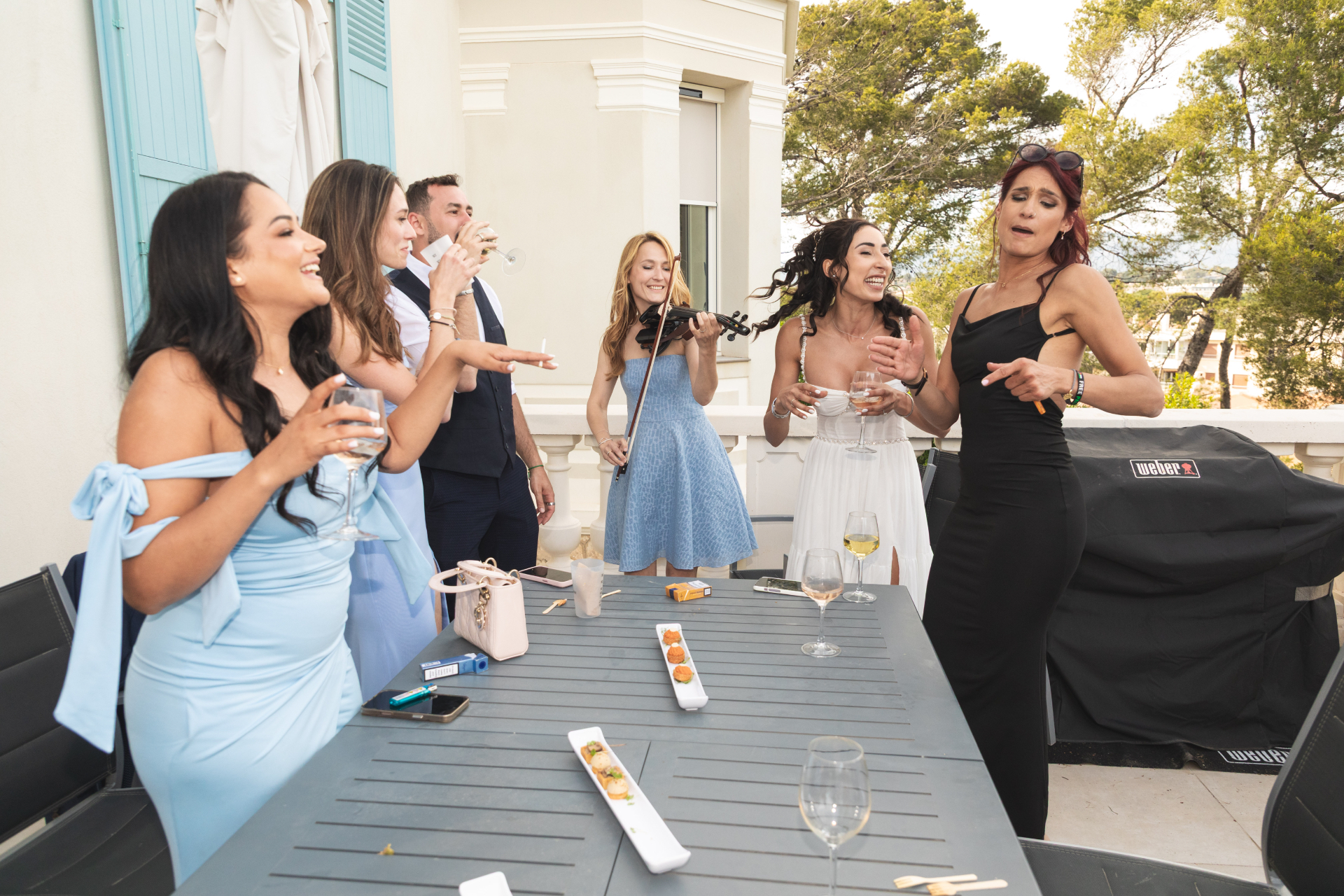 Violoniste String Prod animant un cocktail de mariage sur une terrasse de villa avec vue, invités joyeux à la Côte d'Azur